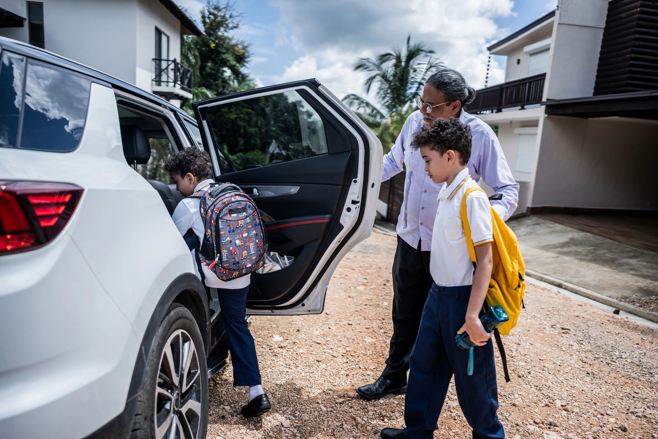 Adult helping children get out of a car at school